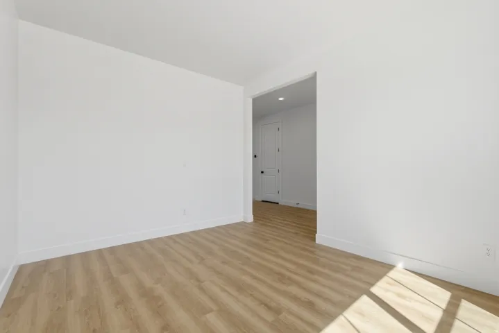 Bright interior space featuring wood-finish flooring, white walls, and clean white baseboards