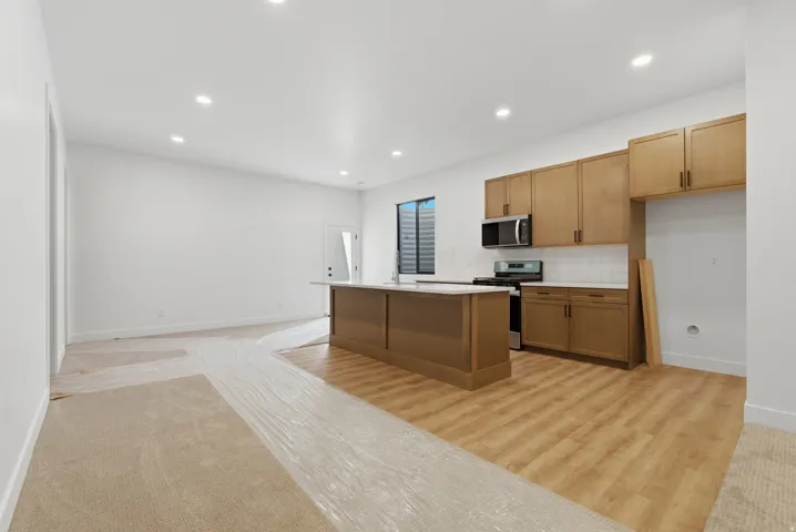 Open-concept kitchen featuring wood-finish flooring and a central island with a white countertop