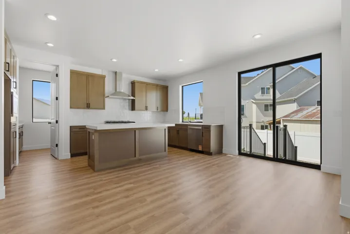 Open-concept kitchen and living area featuring wood-finish flooring, recessed lighting, and a kitchen island with a built-in cooktop