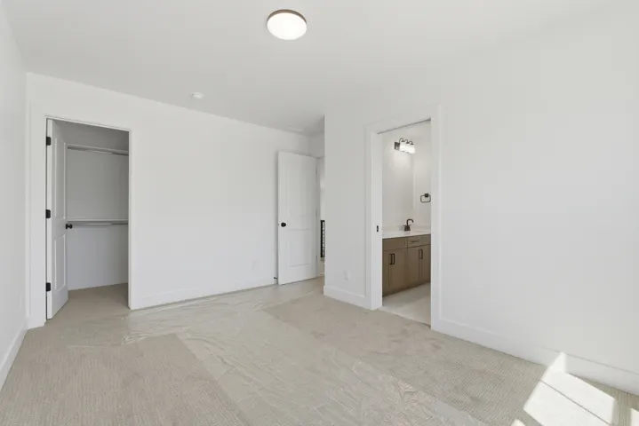 Spacious room featuring light-toned carpet flooring, a flush-mount ceiling light, and white walls
