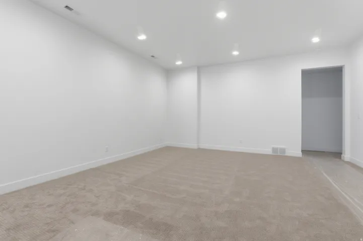 Spacious room featuring neutral carpet flooring, white walls, recessed lighting, and white baseboards