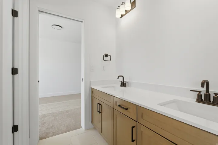 Dual vanity with light wood-finish cabinetry, white countertop, and integrated sinks