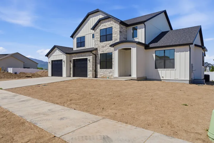 Contemporary exterior featuring board and batten siding, stone accents, black-framed windows, and a covered entry