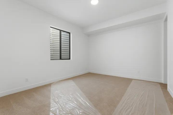 Neutral-toned carpet flooring in a bright room featuring a single window with blinds and white walls