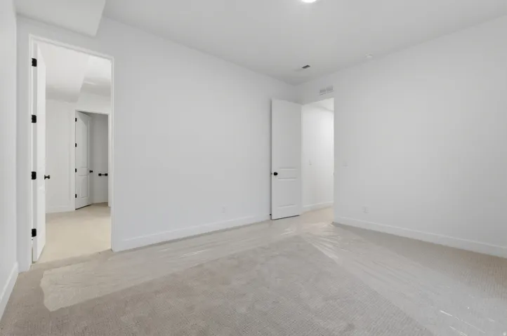 Neutral-toned carpeting in a room with white walls, baseboards, and ceiling