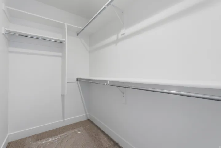 Closet featuring white shelving, chrome hanging rods, and carpet flooring