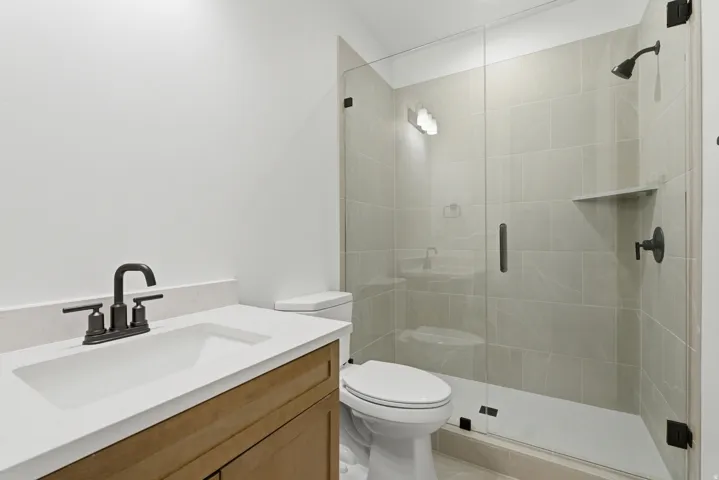 Contemporary bathroom featuring a walk-in shower with clear glass enclosure and light-toned tile surround