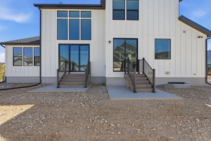 Contemporary exterior featuring white vertical siding, black-framed windows, and a black roof
