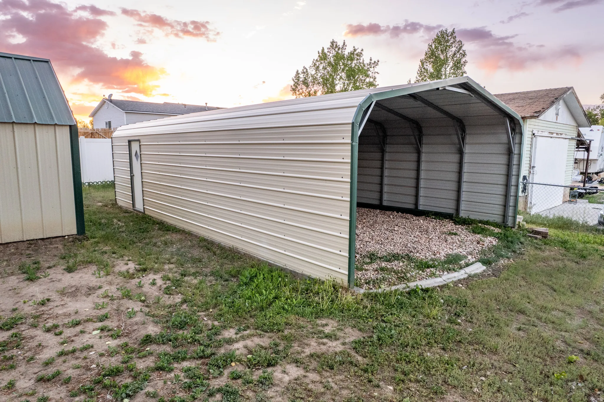 Open-sided metal carport with gravel flooring
