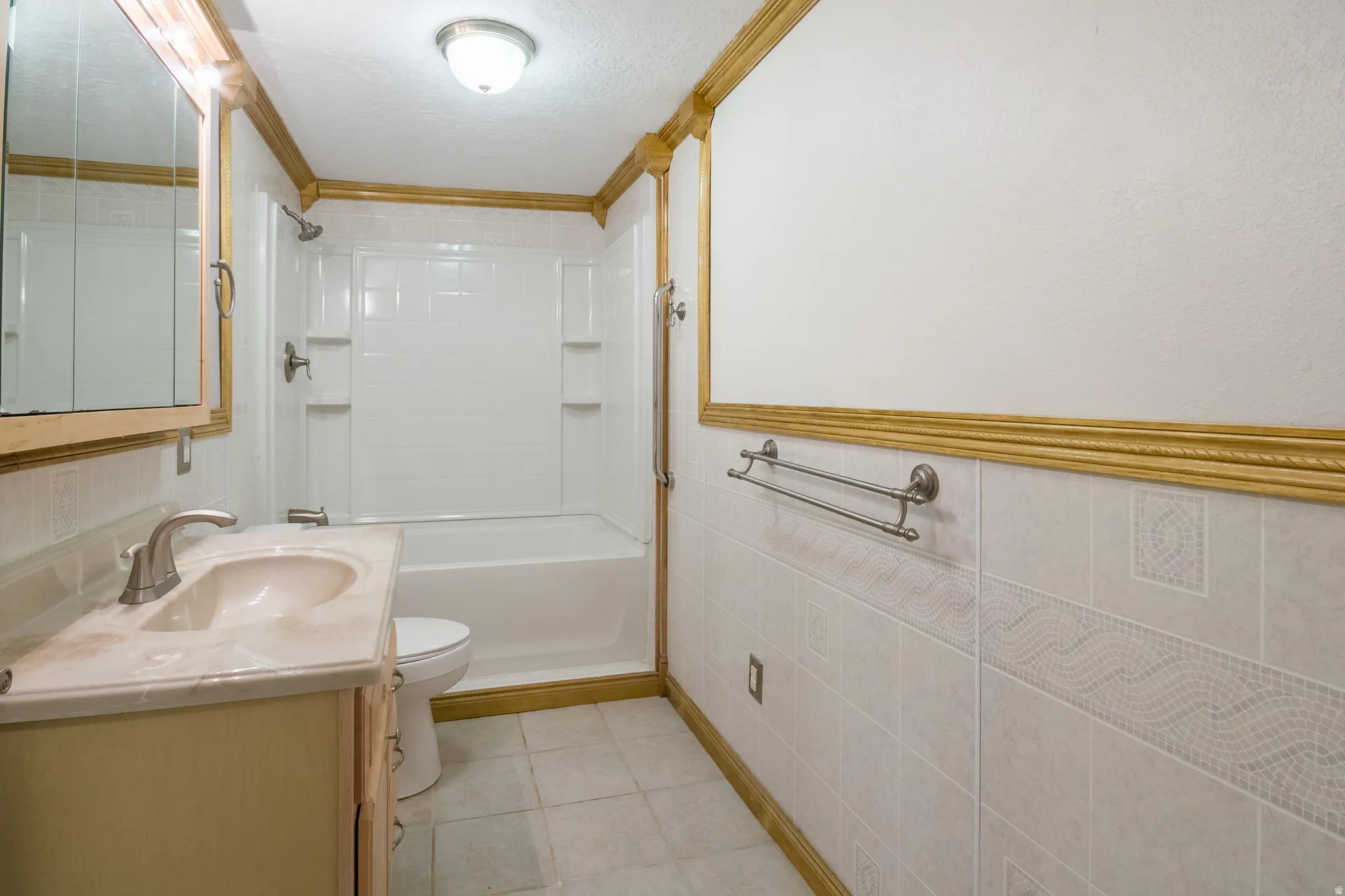 Full bathroom featuring a single vanity with an integrated sink, a built-in bathtub with shower, and decorative wall tiling