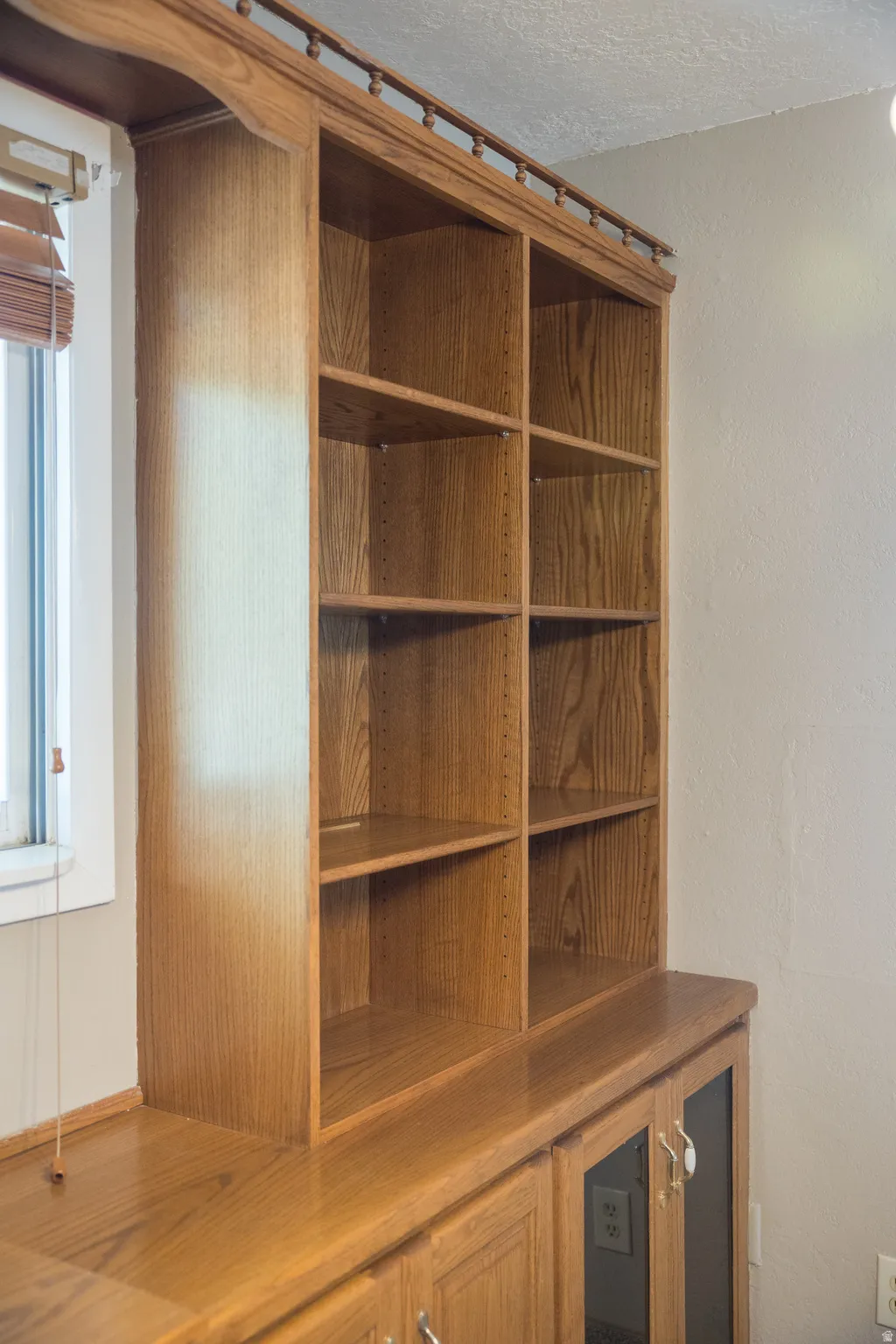 Built-in wood-finish cabinetry featuring open shelving, base storage with glass-front doors, and a wood-finish countertop