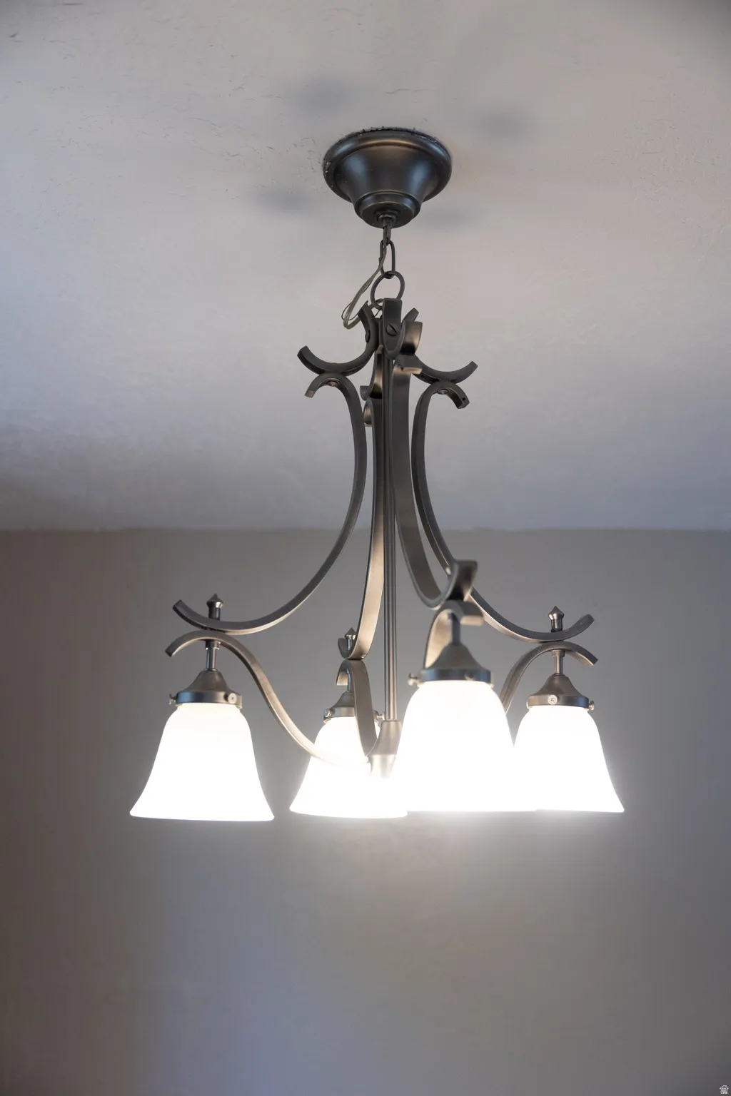 Bronze-finish chandelier with four frosted glass bell-shaped shades