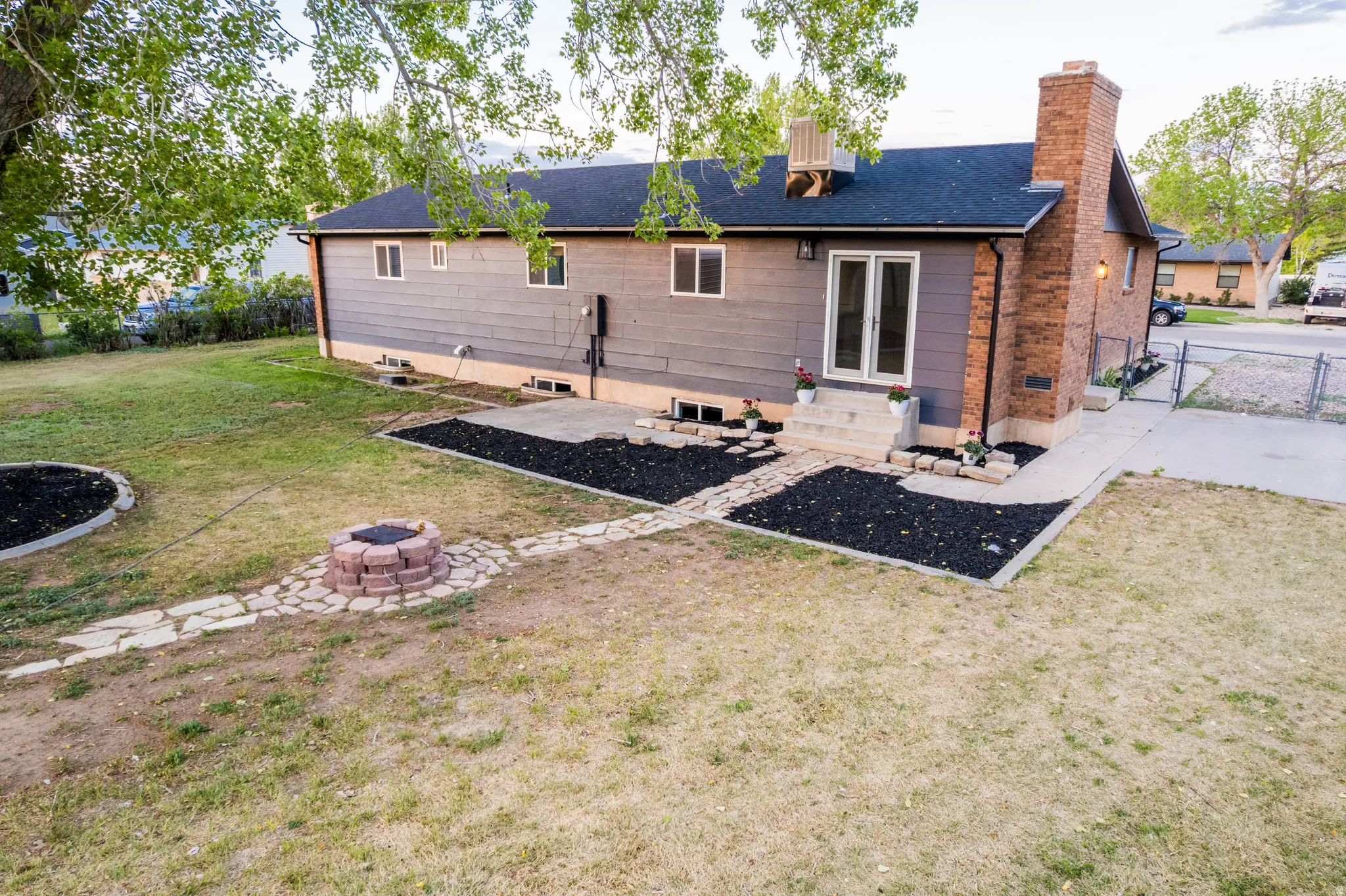 Rear exterior featuring a brick chimney, a double glass-panel door, and a concrete patio