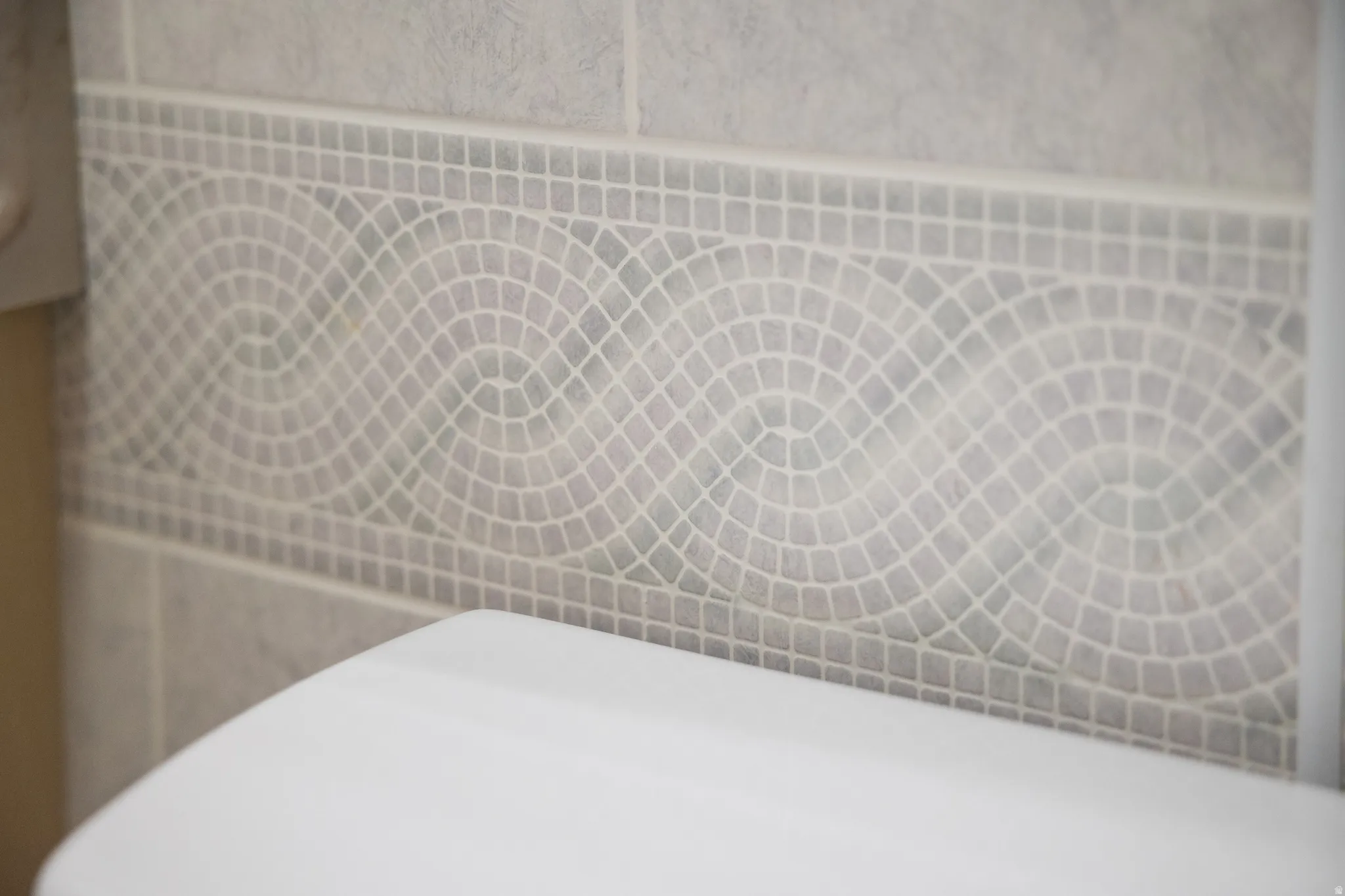 Tile wall accent featuring mosaic pattern and light grout