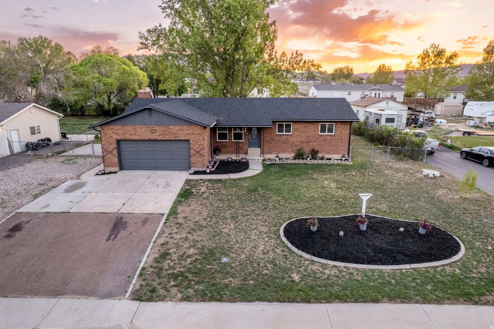 Brick exterior featuring a dark gray garage door, a black asphalt shingle roof, and a concrete driveway