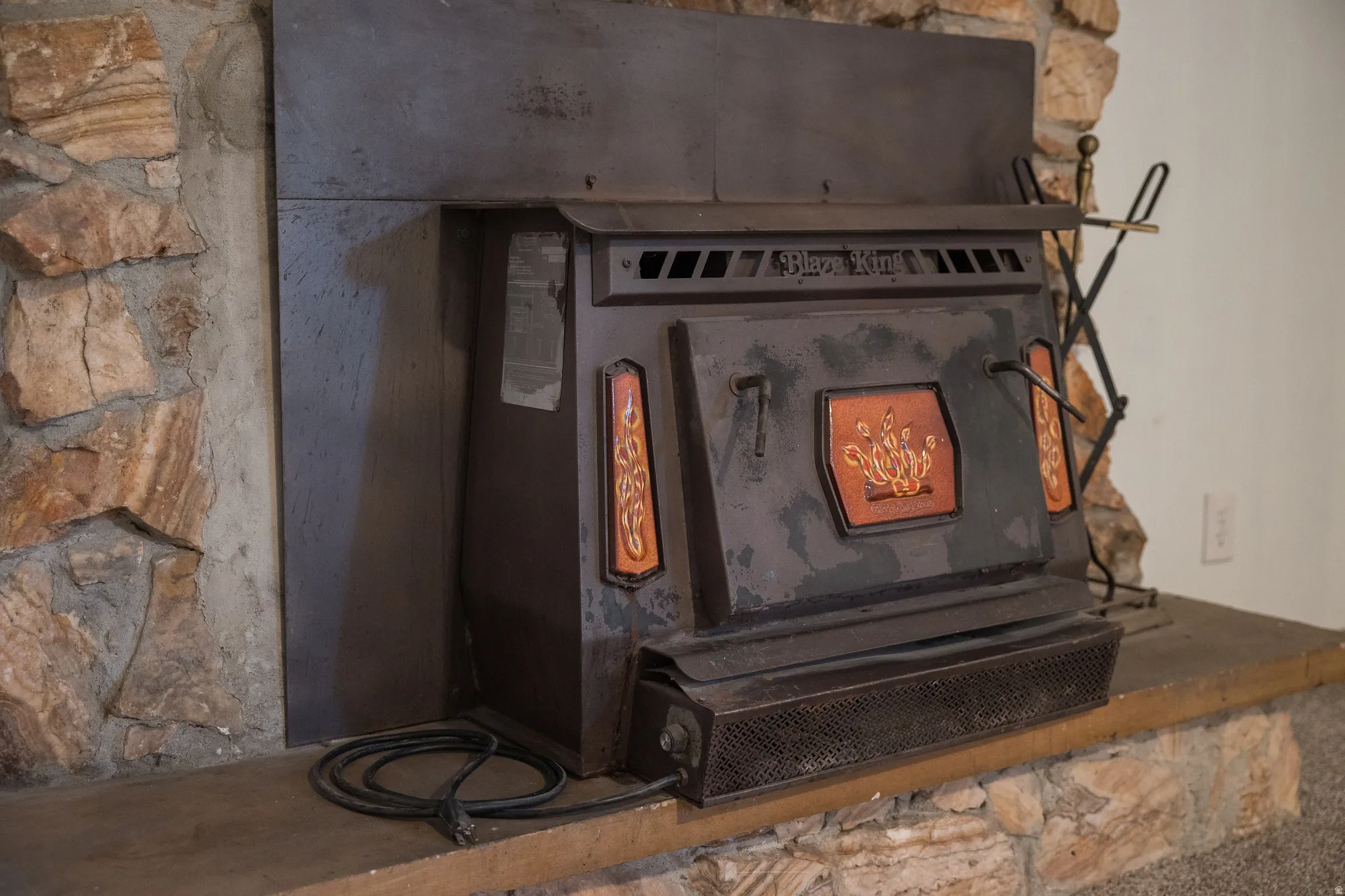 Stone fireplace surround featuring a built-in wood-burning stove with decorative detailing
