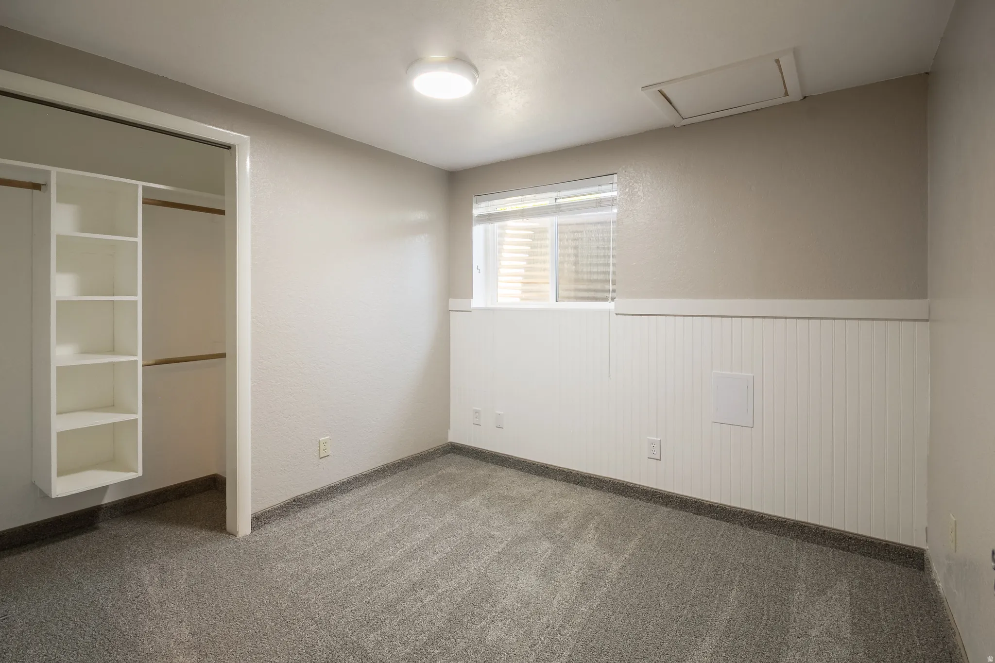 Room with gray carpet, beadboard wainscoting, and a window with blinds