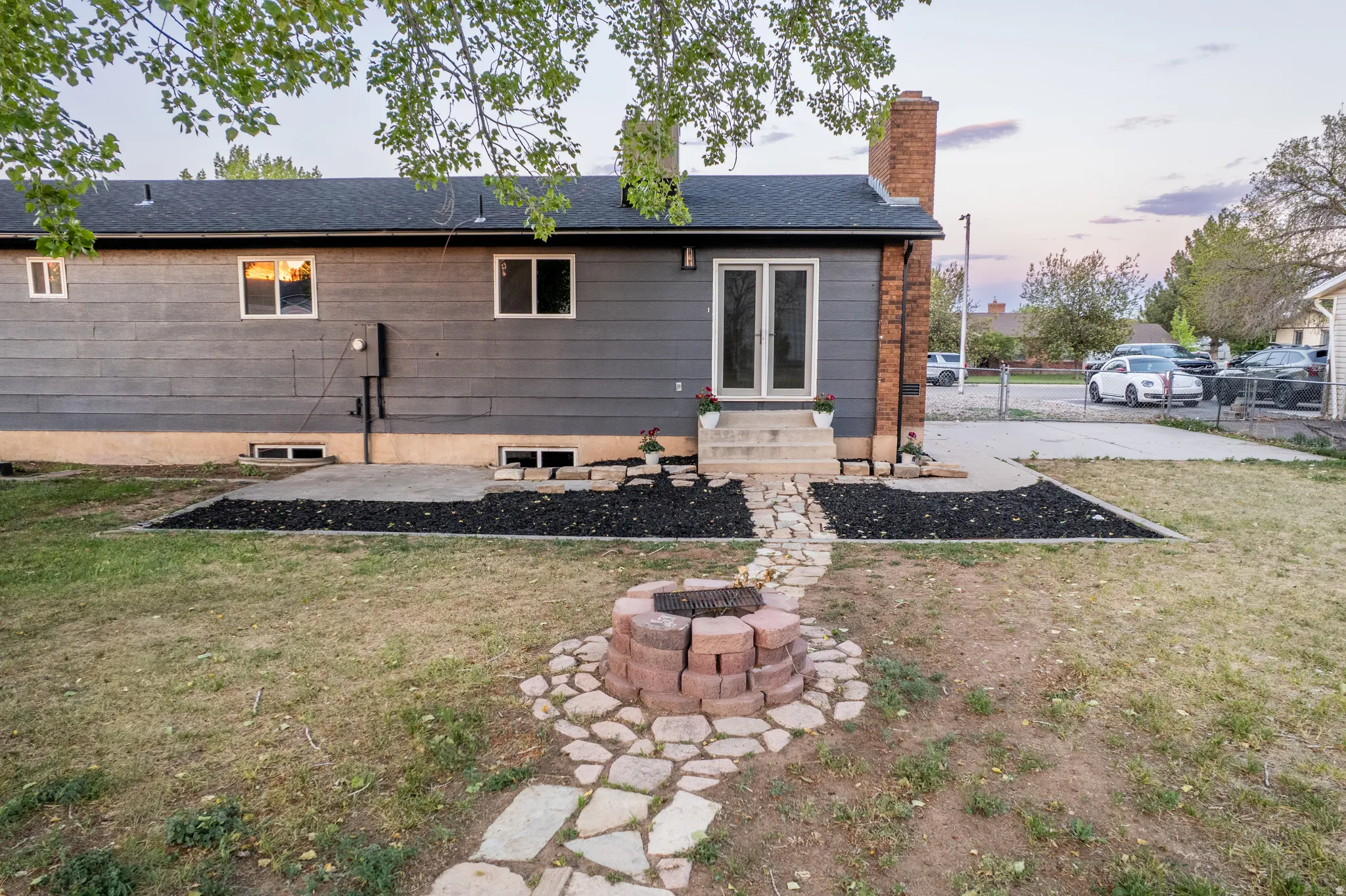 Backyard featuring a stone fire pit, flagstone pathway, and a patio with direct access to the interior via double French doors