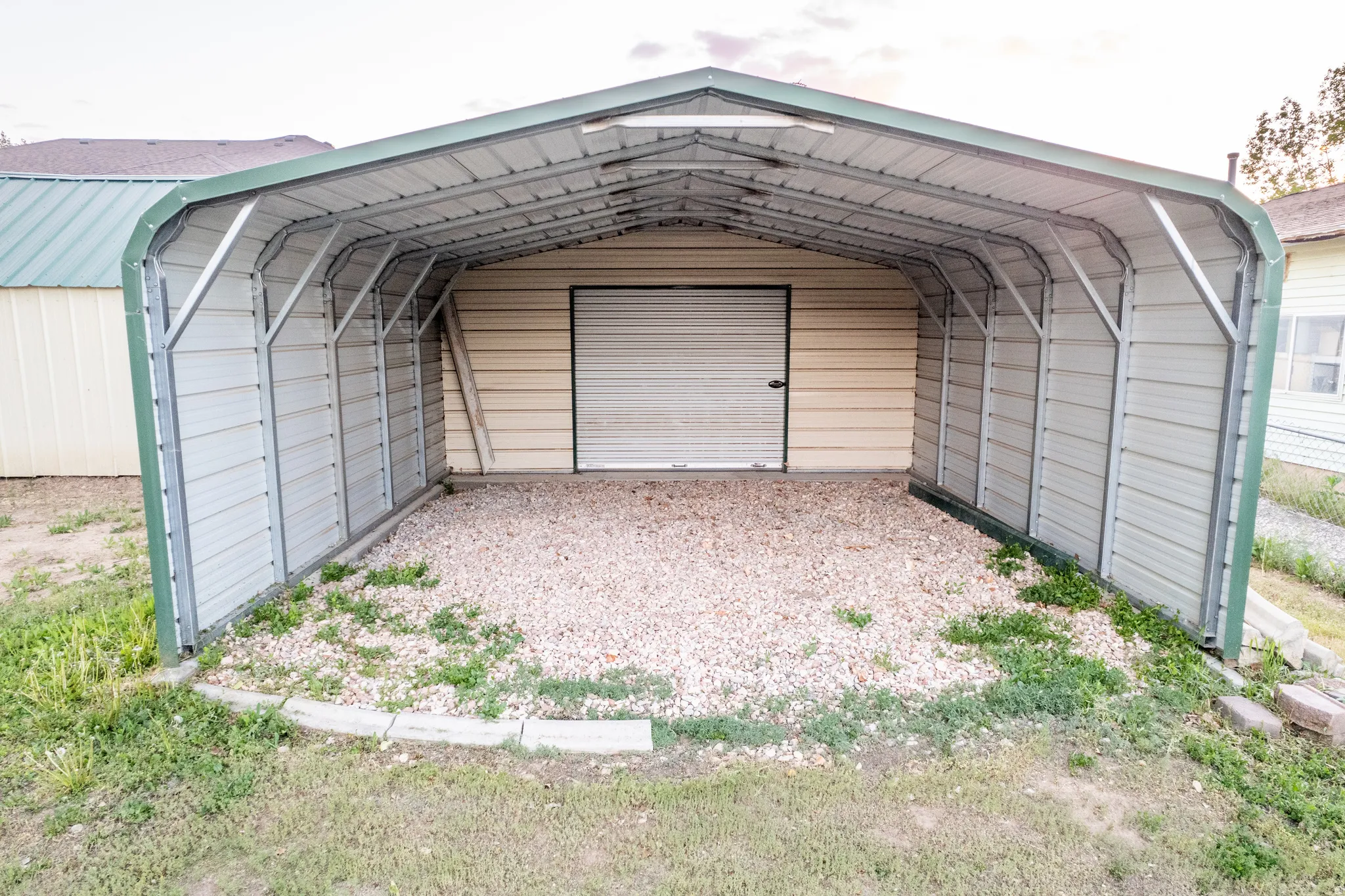 Metal carport structure with a green trim, providing covered parking