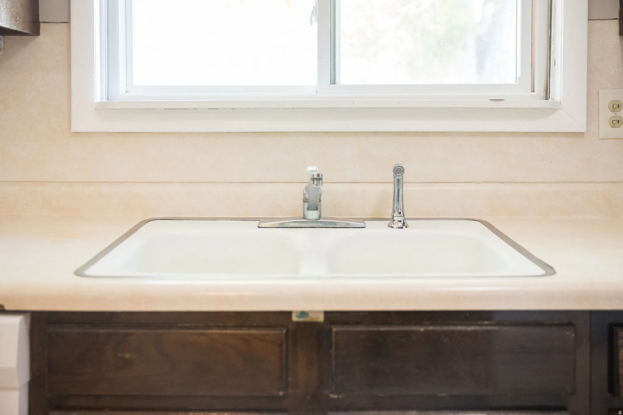 Double basin sink with chrome fixtures, set into a beige countertop