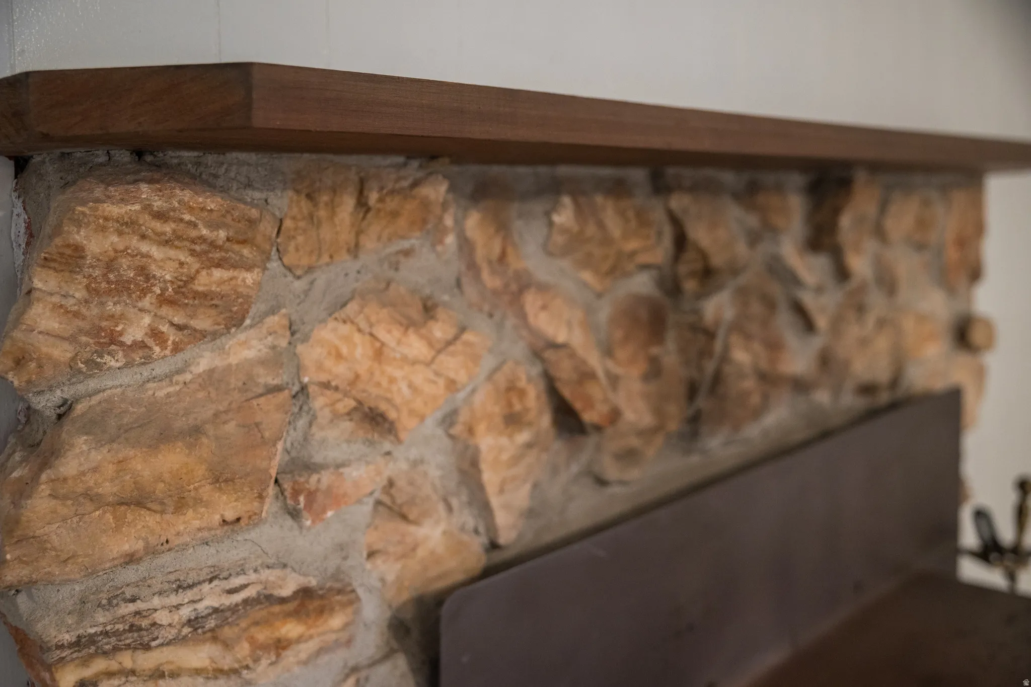 Stone-clad fireplace featuring a rich wood-finish mantelpiece
