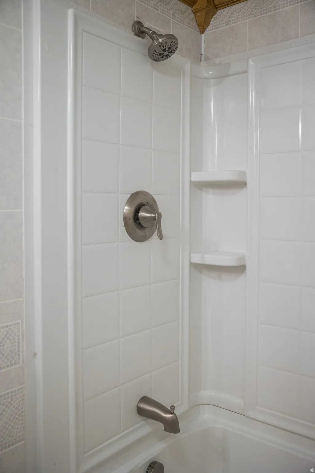 Bathtub and shower combination featuring a brushed nickel showerhead, coordinating brushed nickel tub spout, and a single handle control