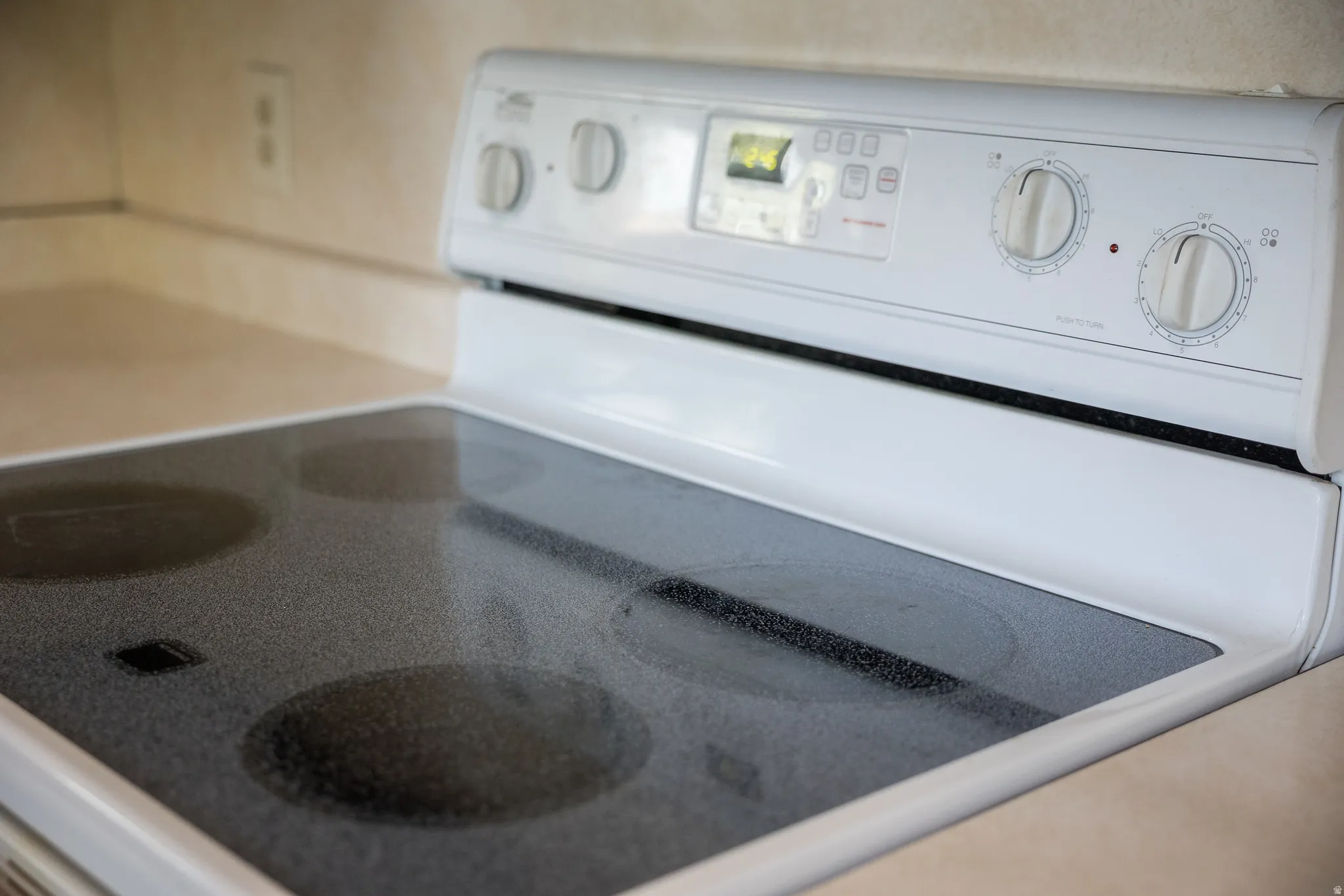 White electric range with a black ceramic glass cooktop and dial controls