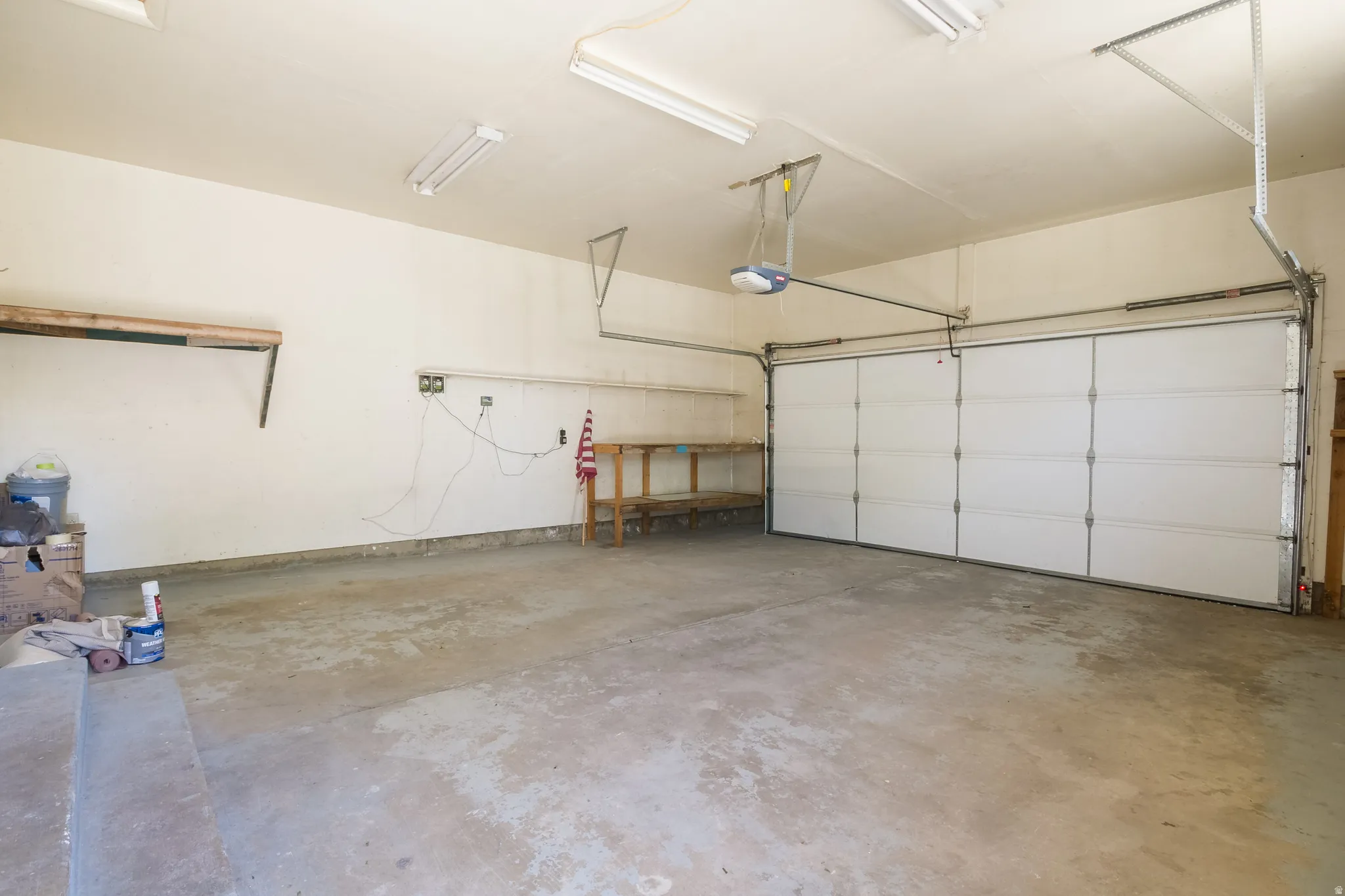 Integrated garage space featuring a concrete floor, overhead fluorescent lighting, and an automatic garage door opener