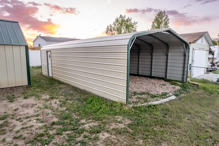 Open-sided metal carport with gravel flooring