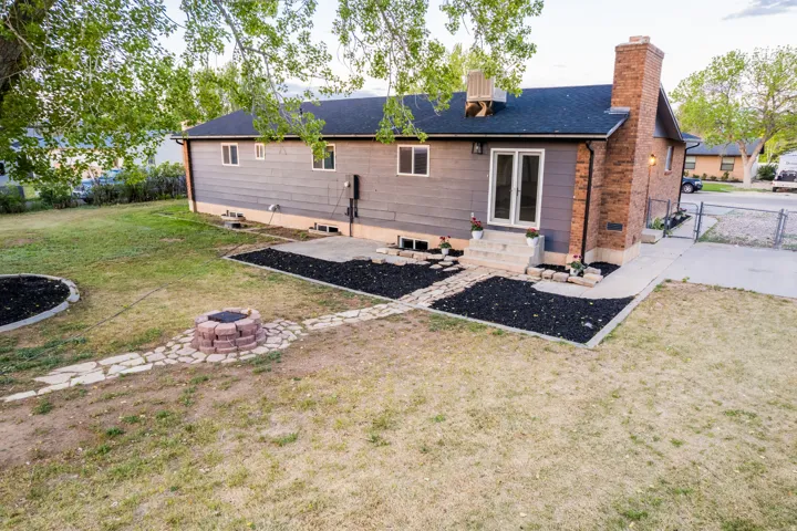 Rear exterior featuring a brick chimney, a double glass-panel door, and a concrete patio