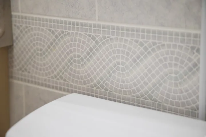 Tile wall accent featuring mosaic pattern and light grout