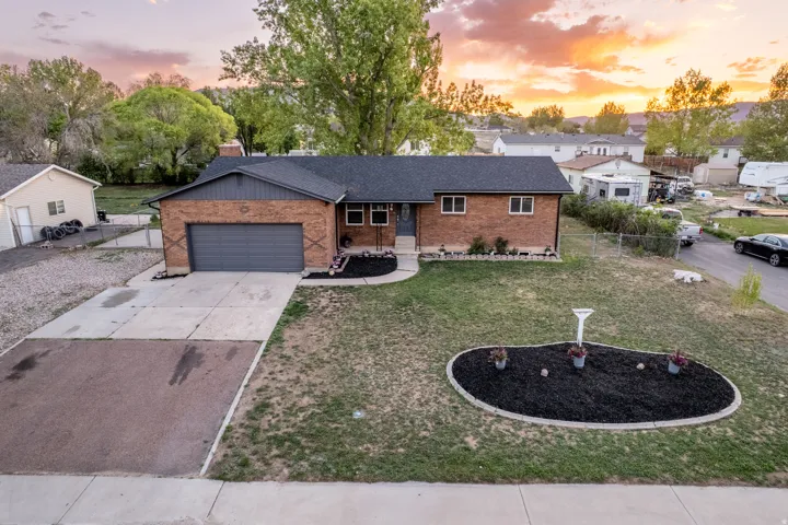 Brick exterior featuring a dark gray garage door, a black asphalt shingle roof, and a concrete driveway