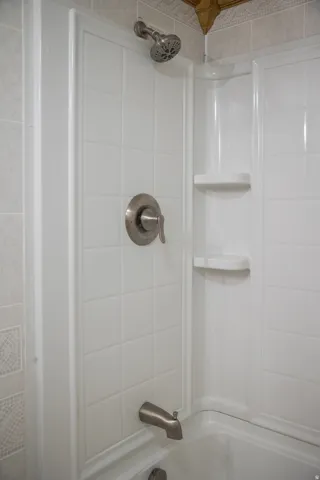 Bathtub and shower combination featuring a brushed nickel showerhead, coordinating brushed nickel tub spout, and a single handle control