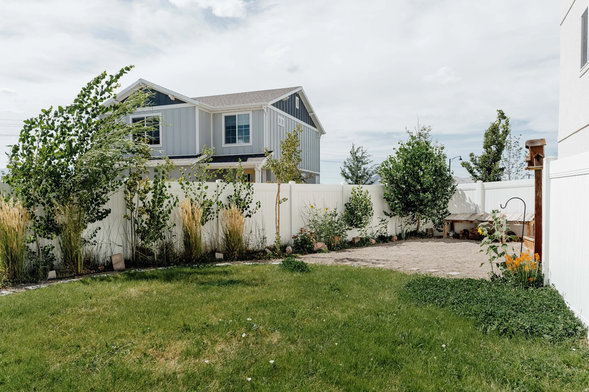 Expansive backyard featuring a green lawn, gravel patio area, and mature perimeter plantings