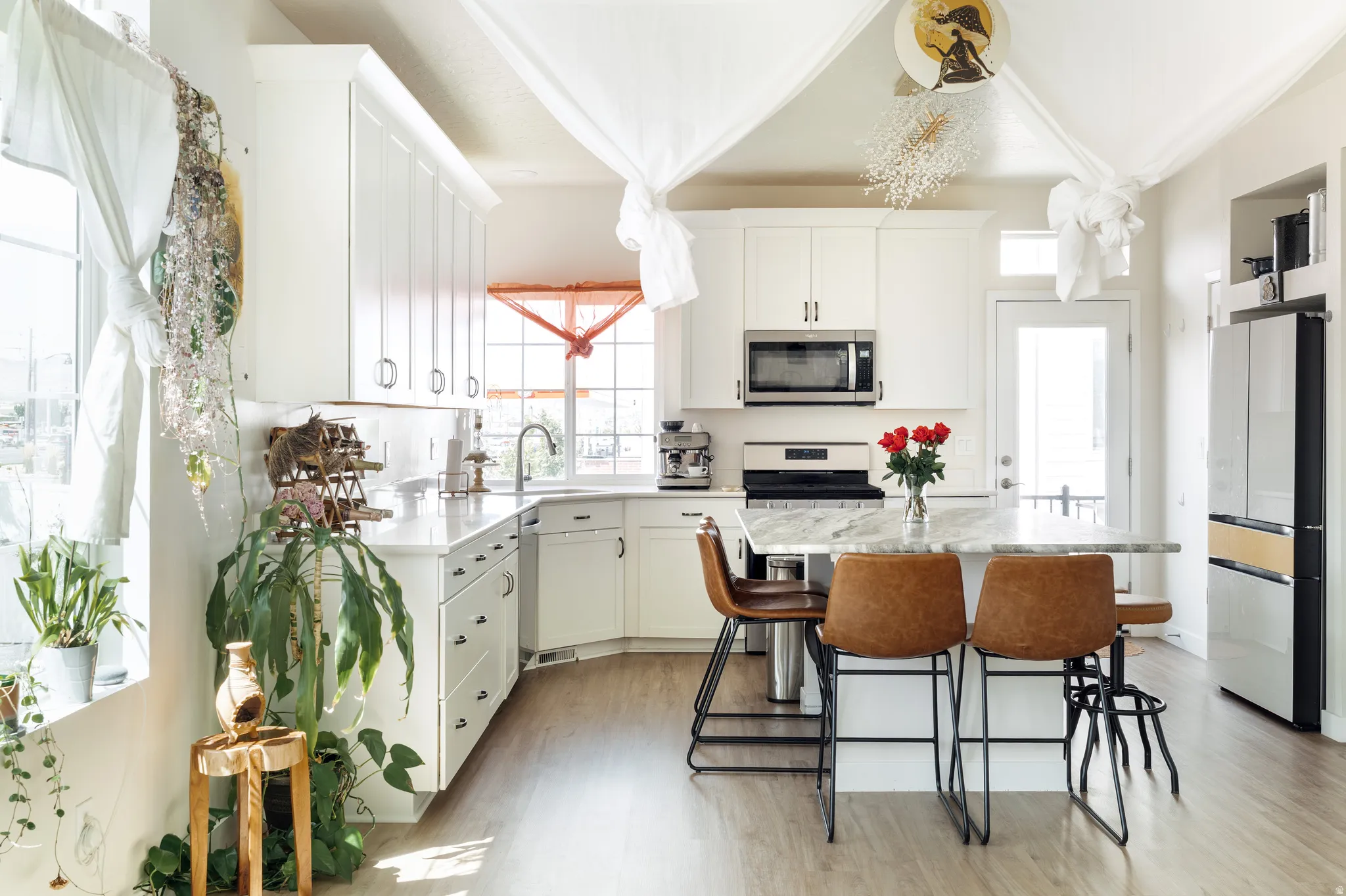 Modern kitchen featuring white cabinetry, light-tone wood-finish flooring, and a central island with a light-toned countertop