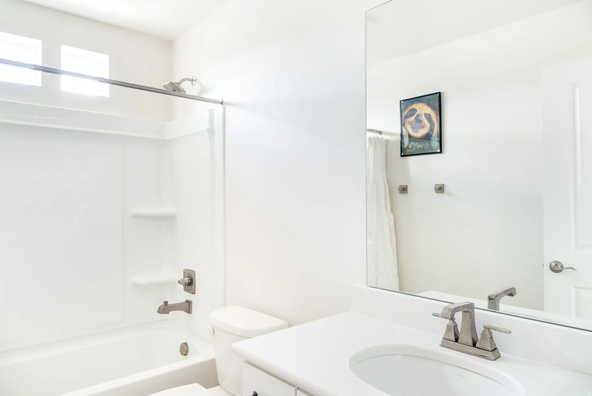Full bathroom featuring a shower-tub combination with built-in shelving, brushed nickel fixtures, and a white vanity with an integrated sink and large mirror