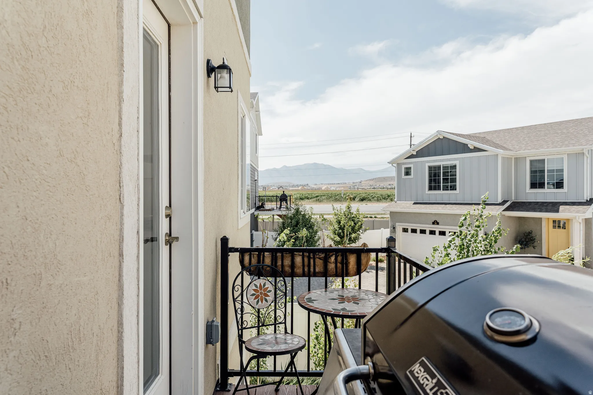 Private balcony featuring a stucco exterior, black metal railing, and an outdoor wall lantern