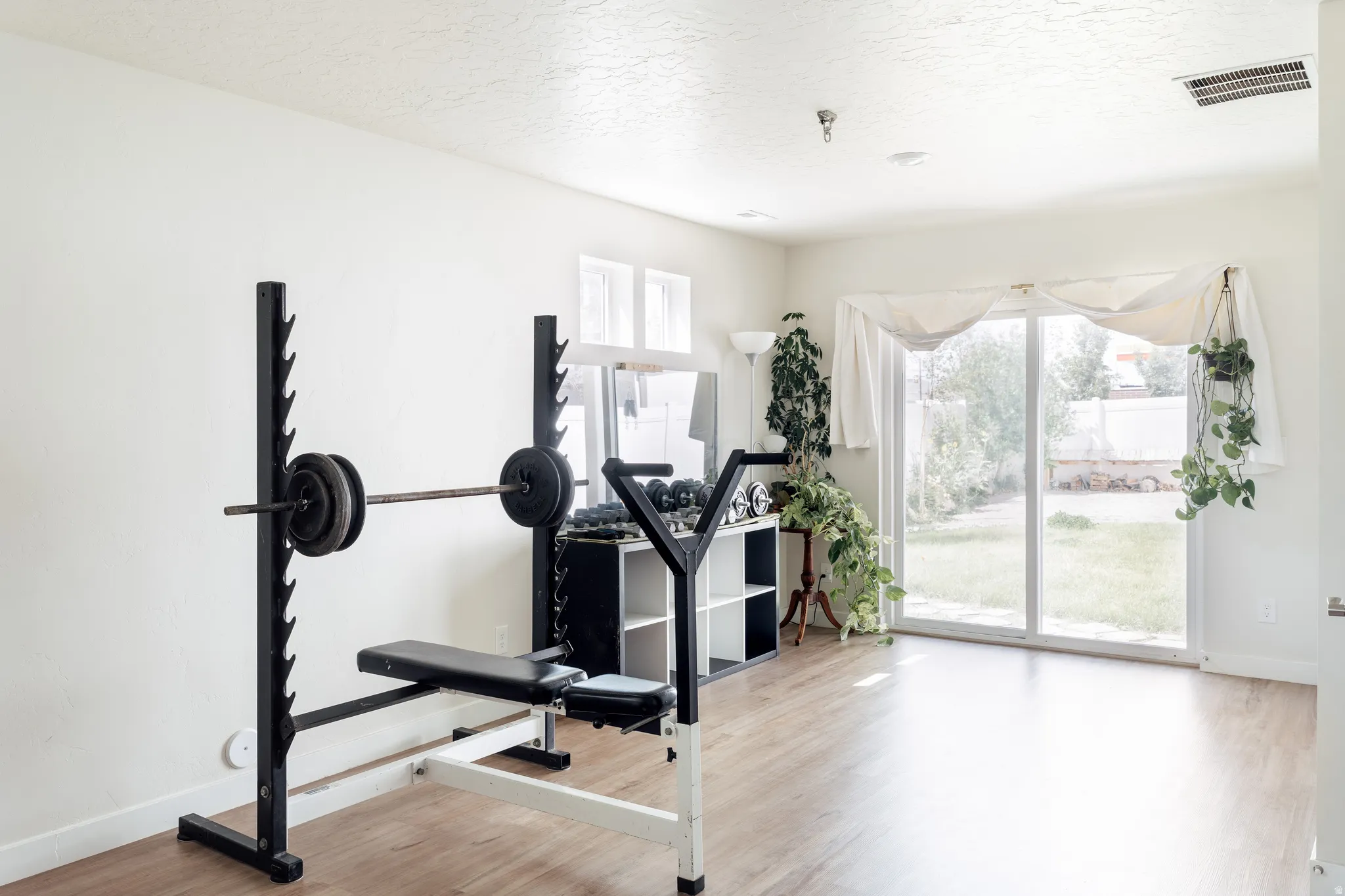 Spacious room with wood-finish flooring, white walls, and a recessed ceiling light