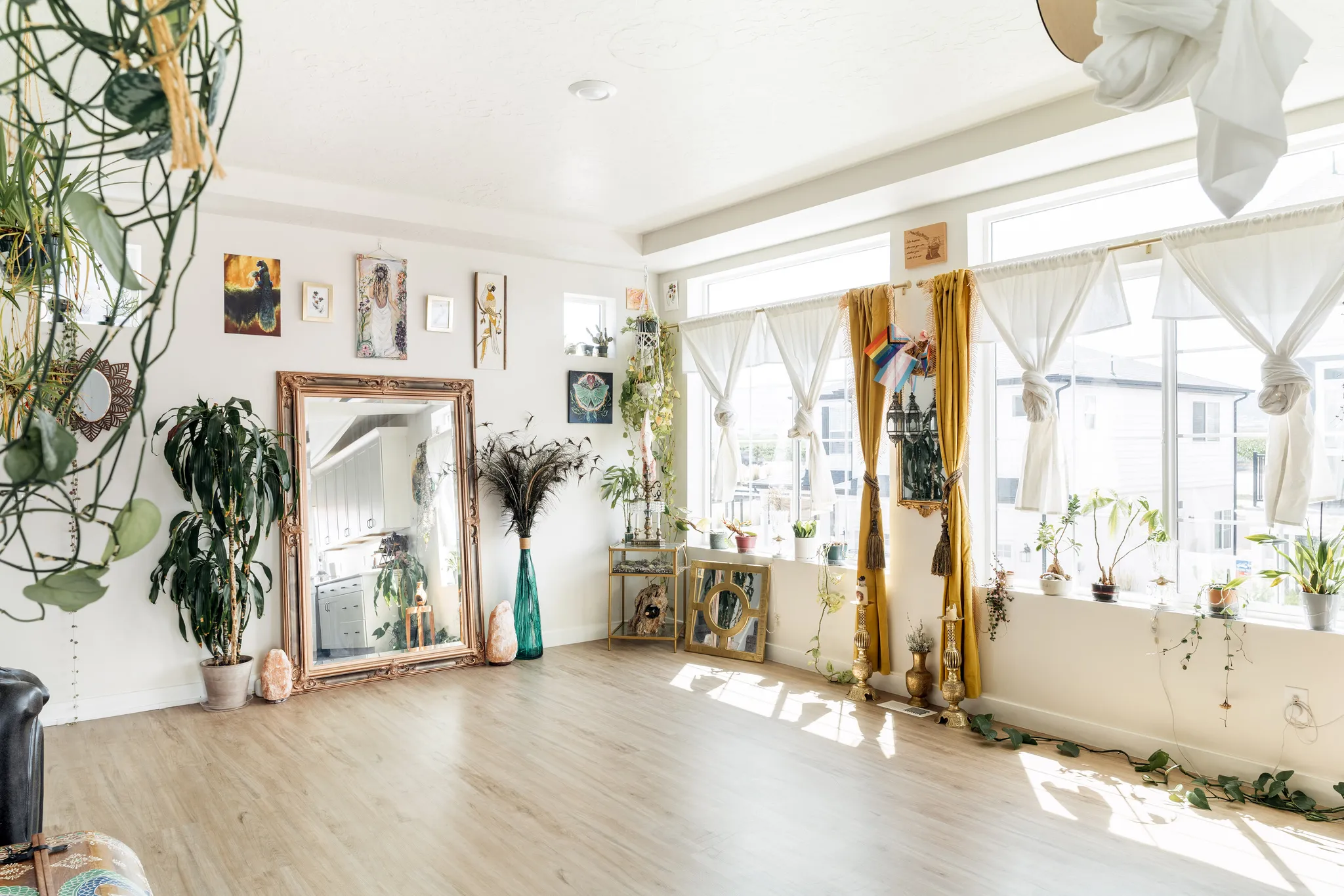Spacious room featuring light wood-finish flooring, abundant natural light from multiple windows, and crisp white walls