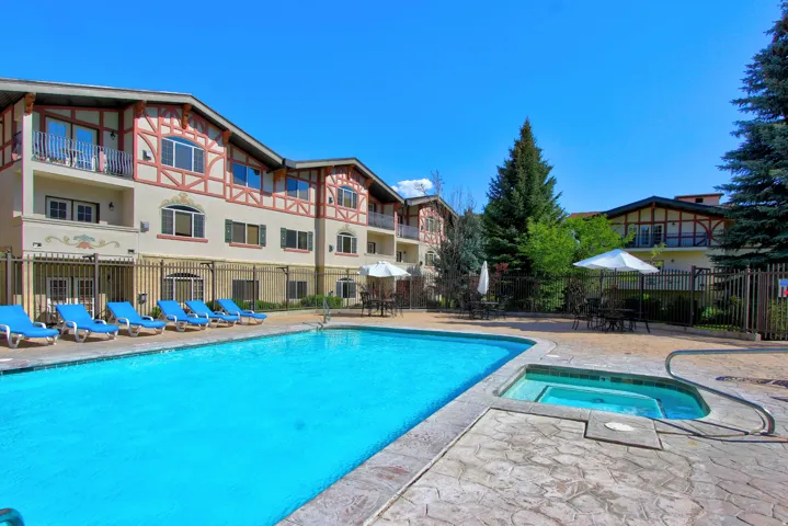 Outdoor swimming pool with integrated hot tub, surrounded by a stamped concrete deck