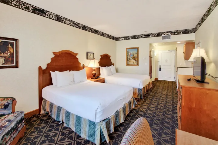 Warm interior featuring two wooden headboards, patterned carpet, and light-toned walls