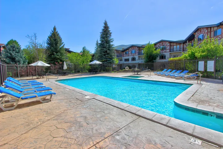 Outdoor swimming pool surrounded by stamped concrete decking and a black metal fence