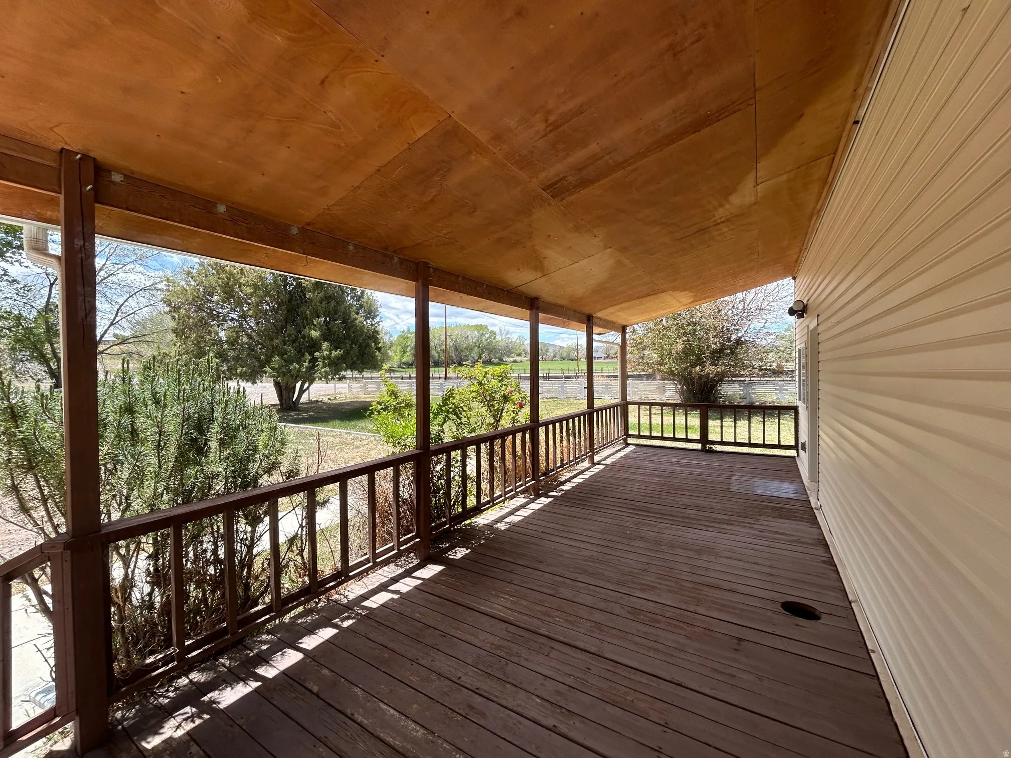 Spacious covered porch featuring wood flooring, wood railing, and a light-toned ceiling