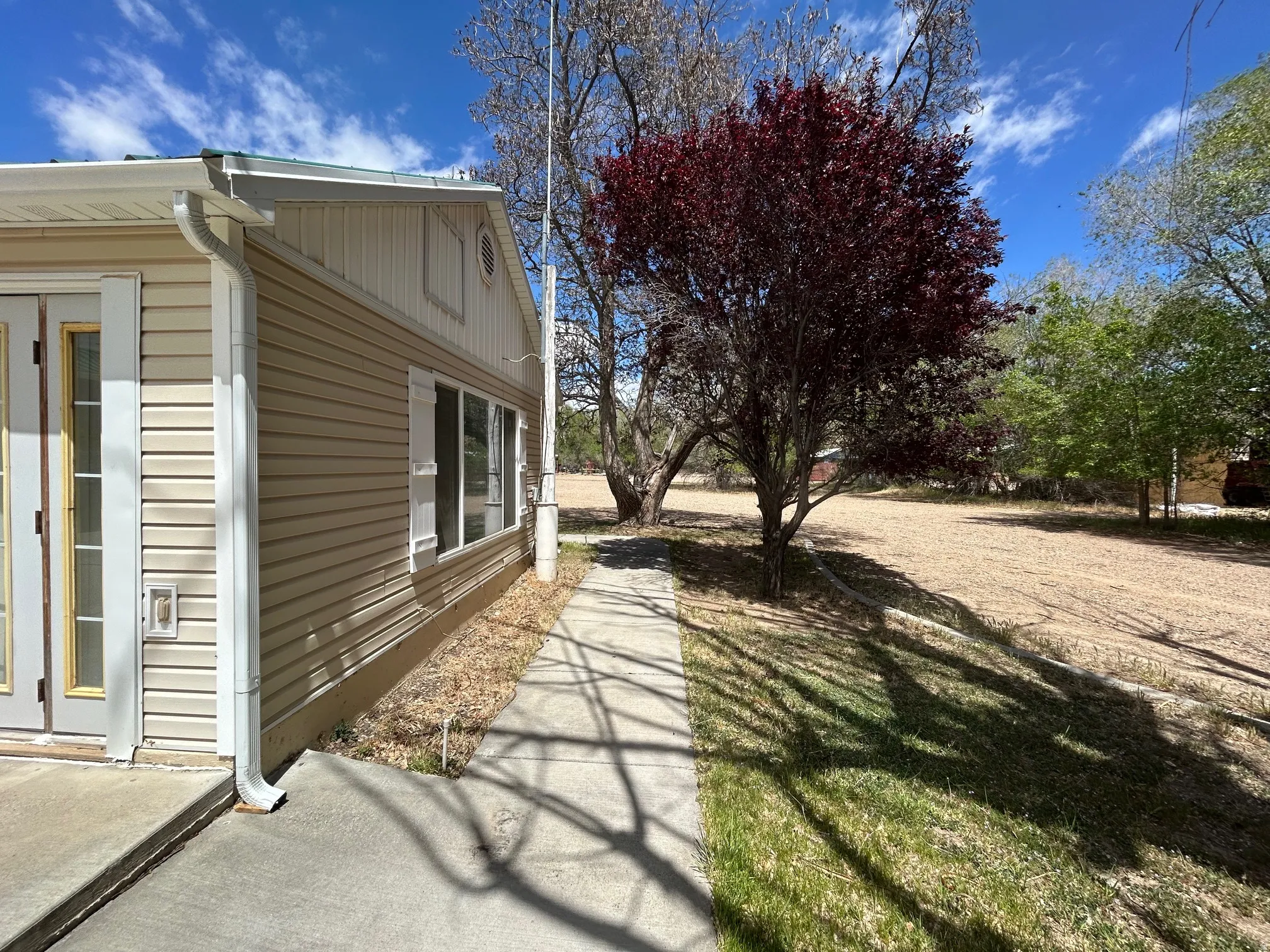 Exterior featuring beige horizontal siding, white trim, and a concrete walkway