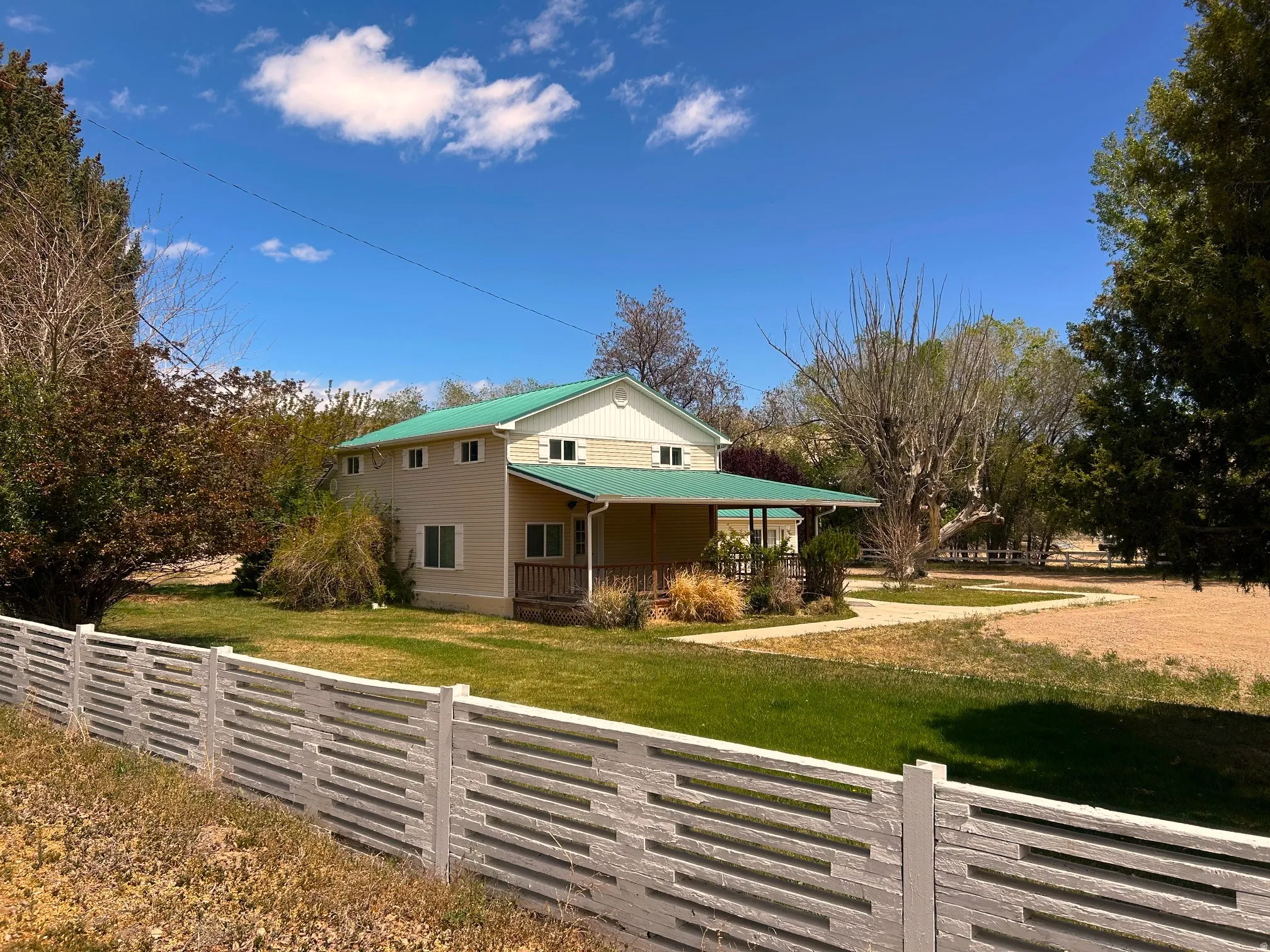 Two-story residence with a green metal roof and a covered porch