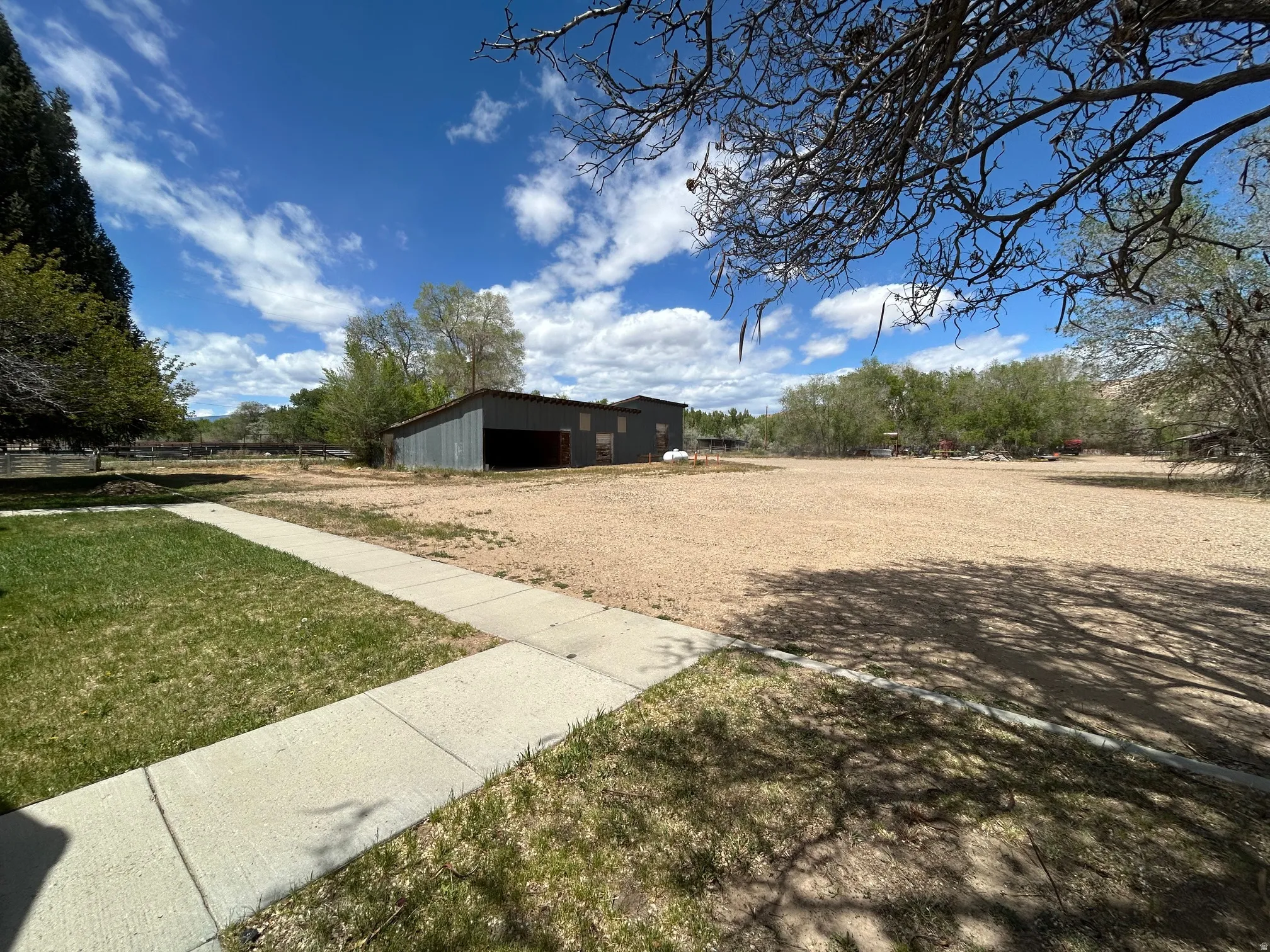Expansive gravel lot featuring a metal-clad barn structure with an open bay