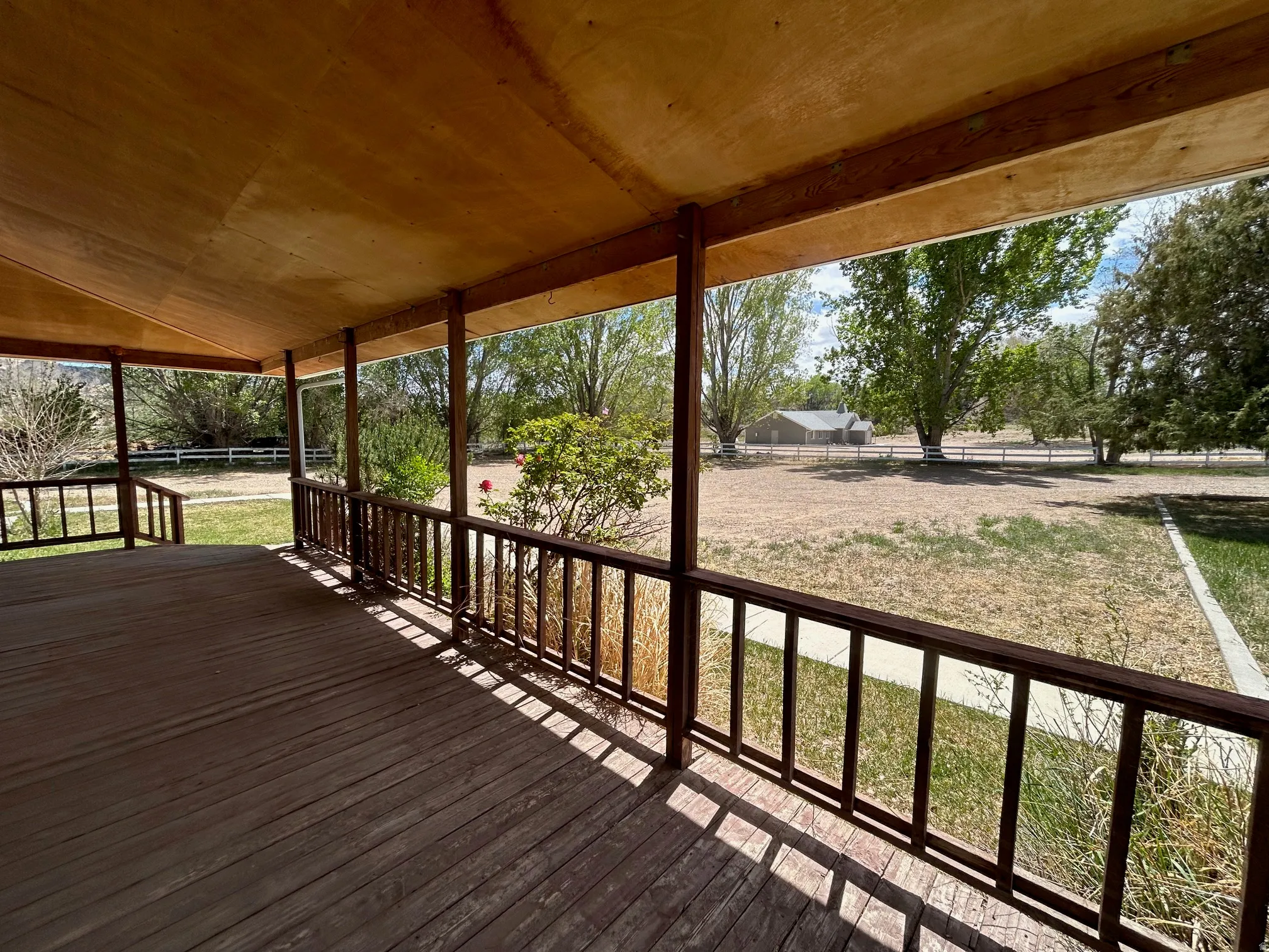 Expansive covered porch featuring a wood-finish deck and ceiling, with wood support columns and railings