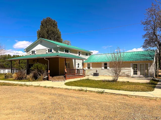 Two-story residence with a green metal roof and a full-length covered porch