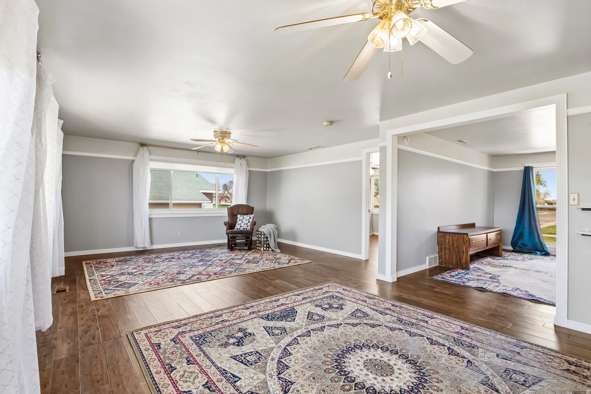 Spacious room featuring wood-finish flooring, light grey walls with white trim, and multiple windows