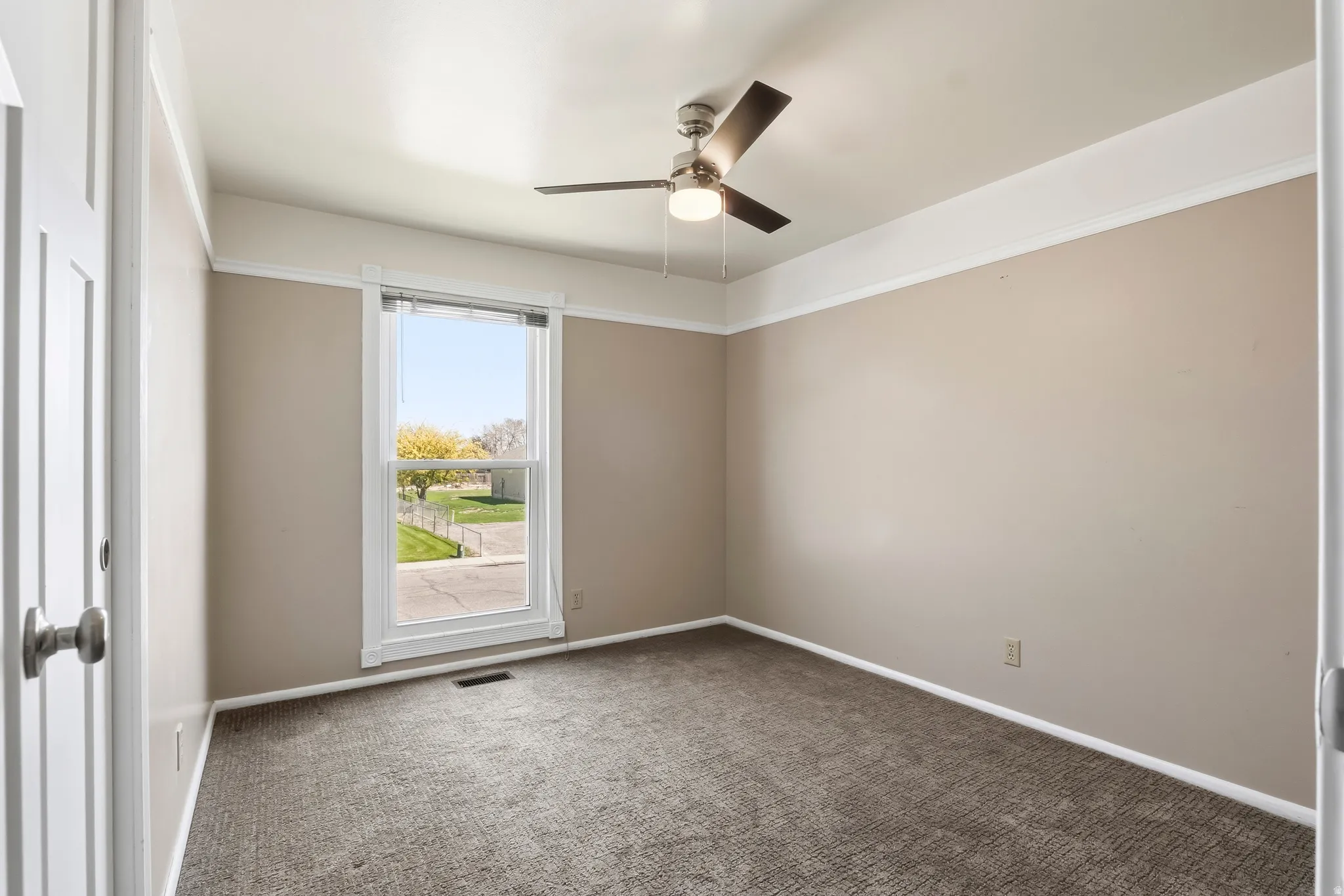 Carpeted room featuring a ceiling fan with integrated lighting, a double-hung window, and neutral wall tones